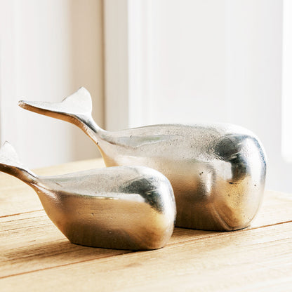 Closeup view of decorative silver metal whale objects, set of 2.