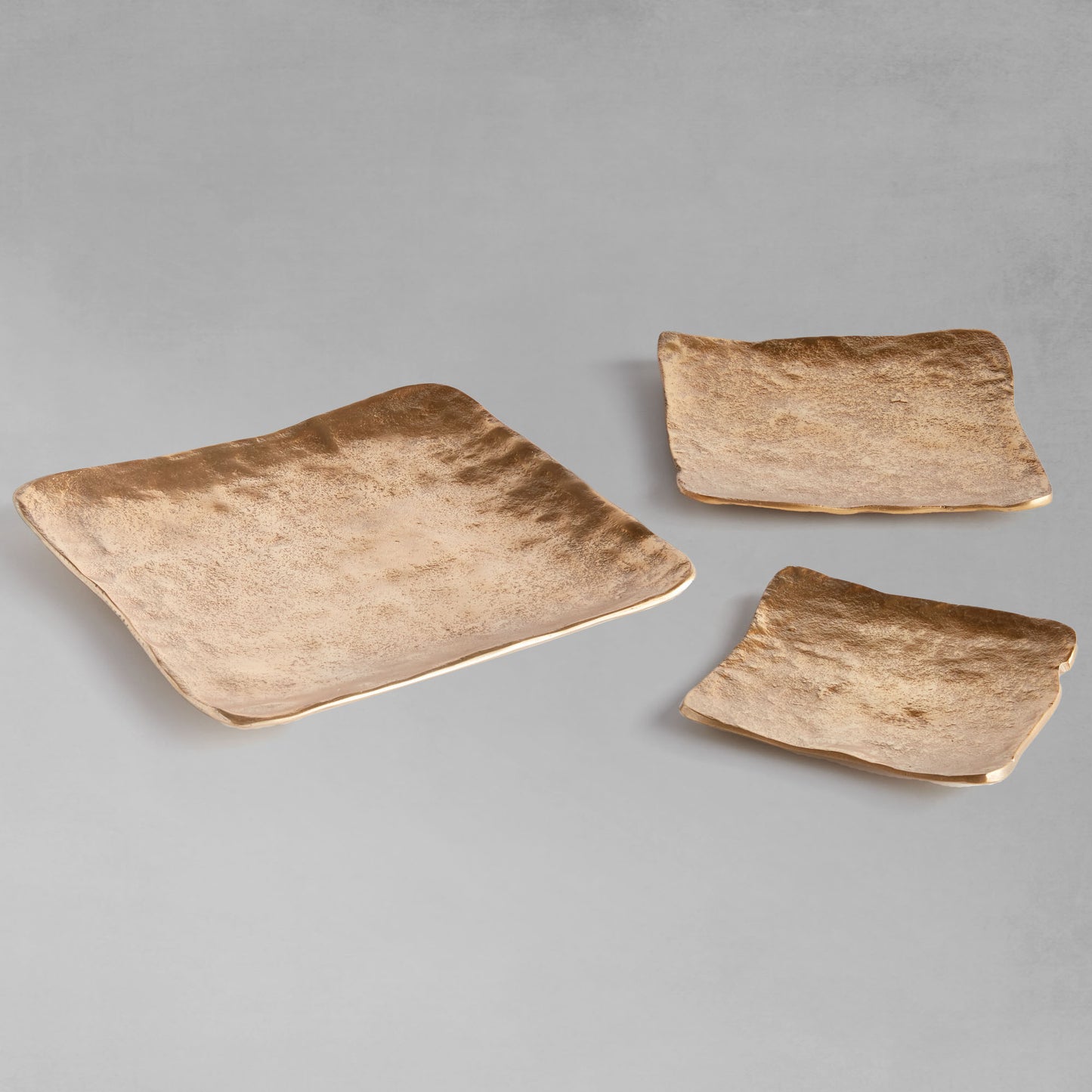 Decorative square metal trays, set of 3, spread out with gray background.