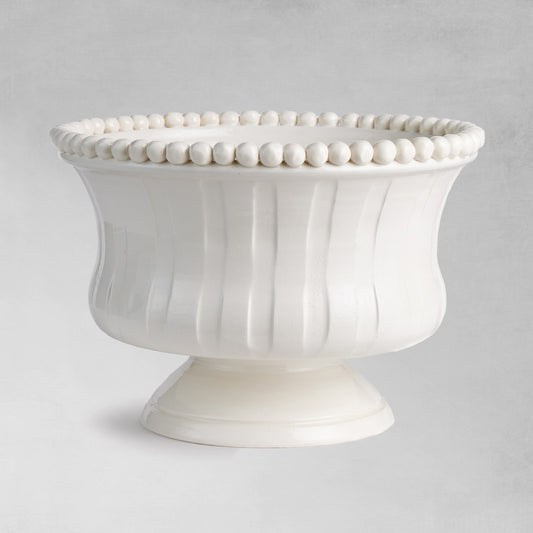 Decorative white ceramic footed bowl with gray background.
