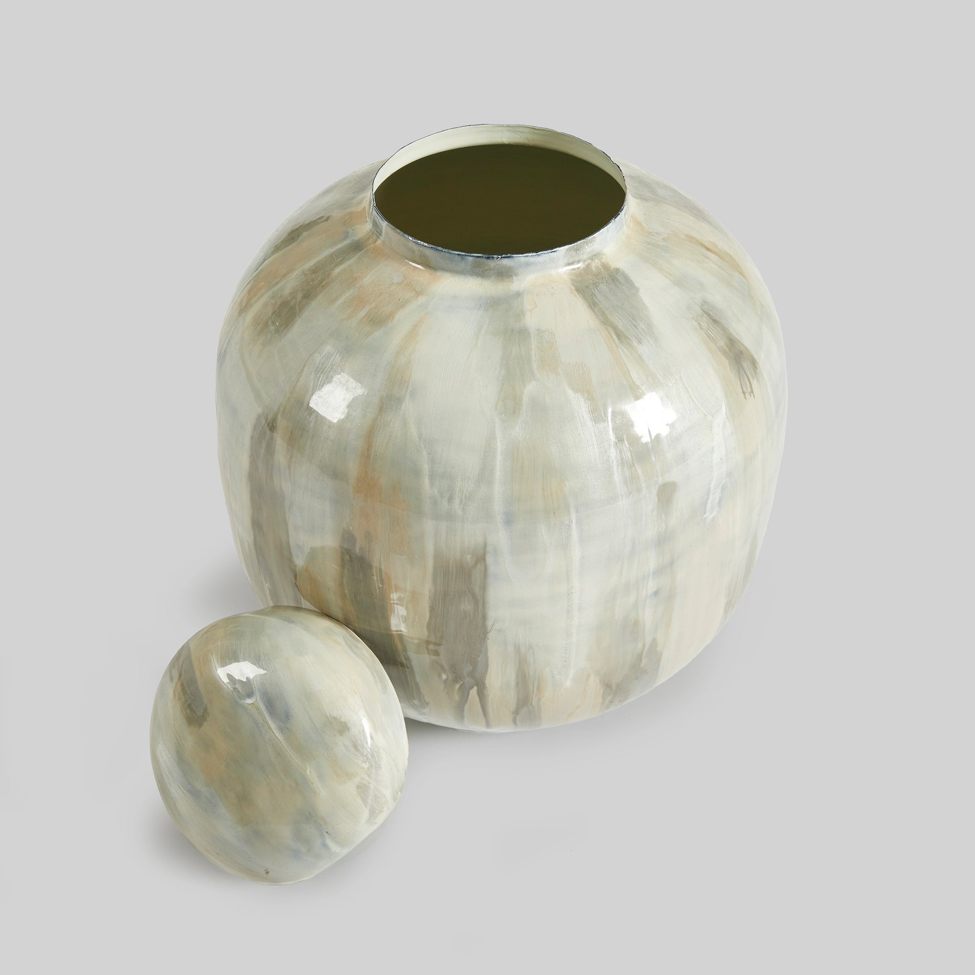 Enamel painted metal decorative jar, with lid removed, with gray background.