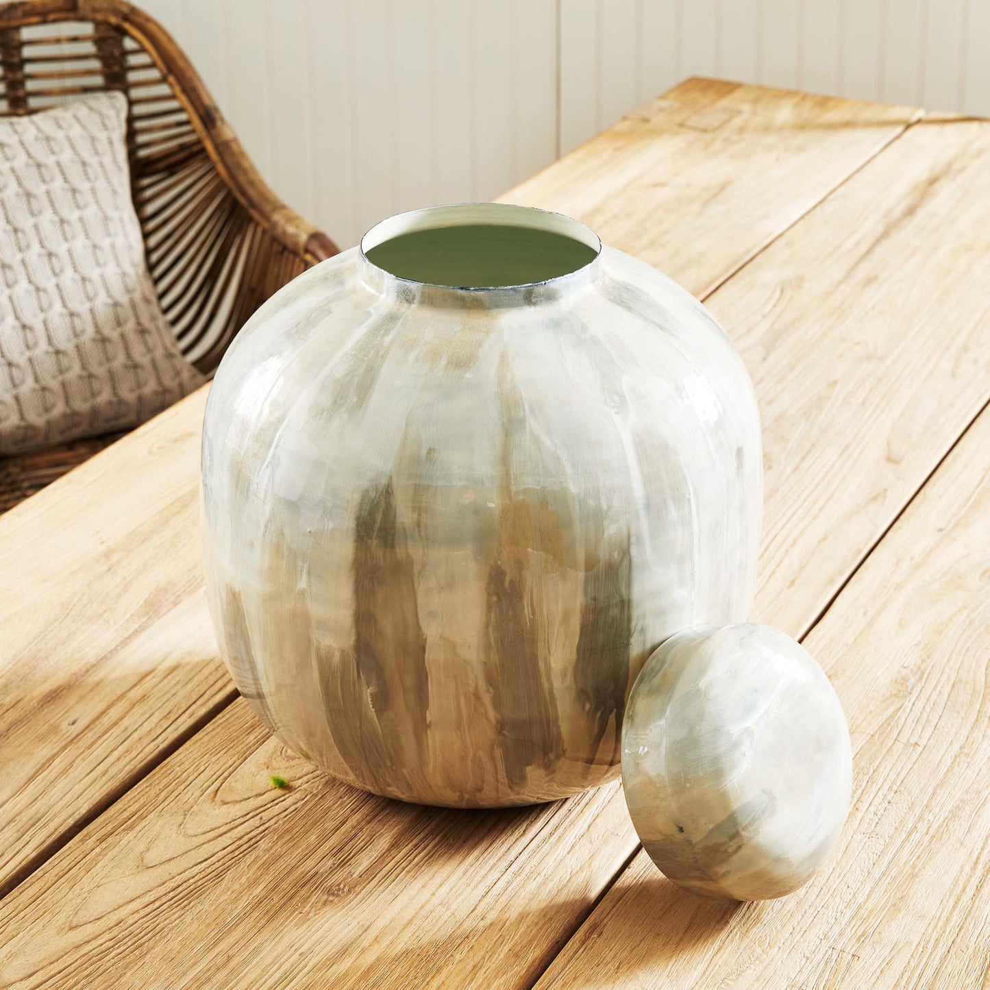 Enamel painted metal decorative jar stylized on wood dining table.