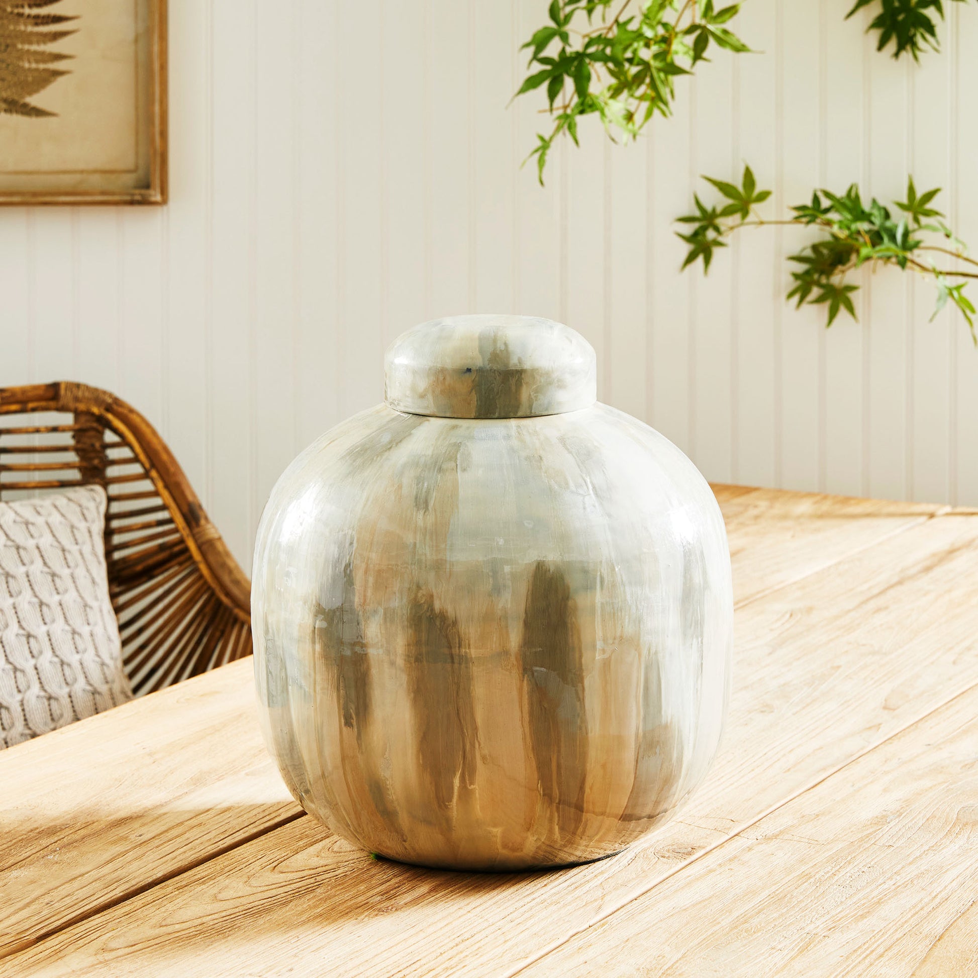 Enamel painted metal decorative jar stylized on wood dining table.