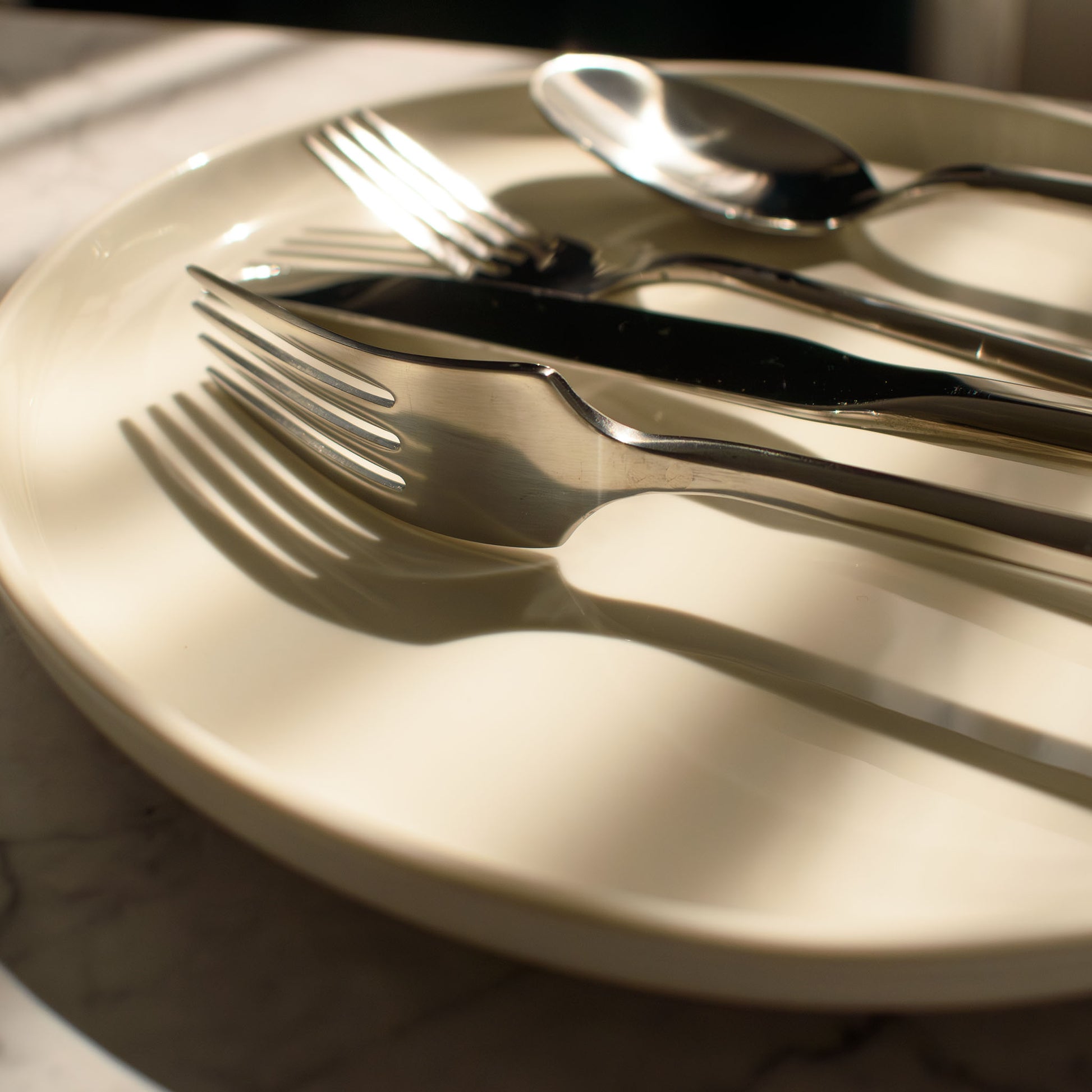 Polished silver hexagonal flatware on plate at golden hour sunset.