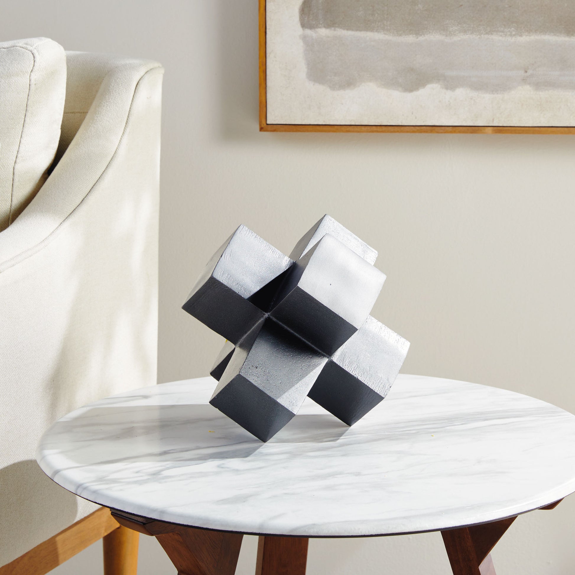 Silver geometric plus sign decorative object stylized on living room side table.