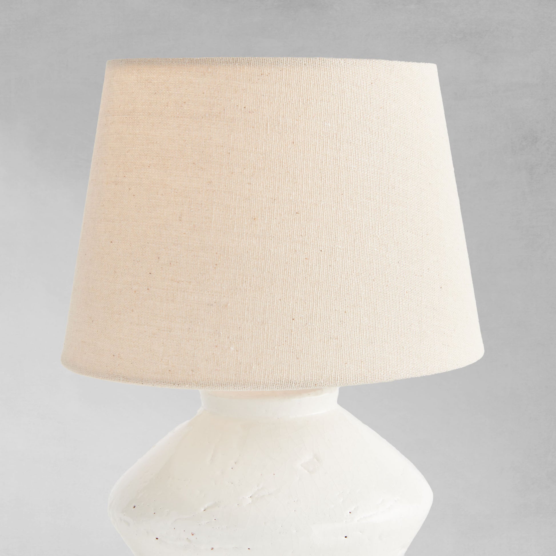 Glazed white mini lamp, closeup view of lampshade, with gray background.