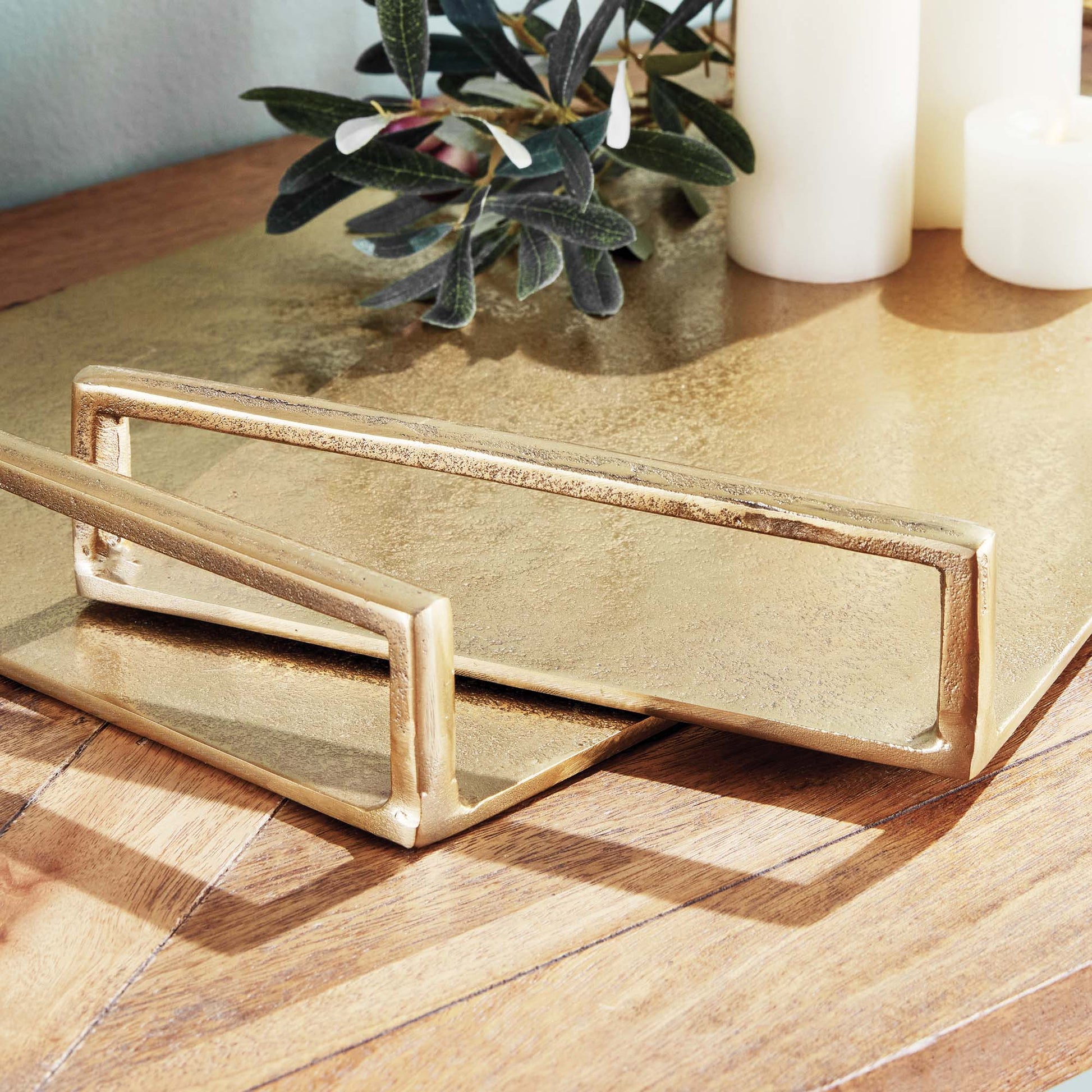 Gold decorative metal trays, set of two, closeup view, stylized on table.