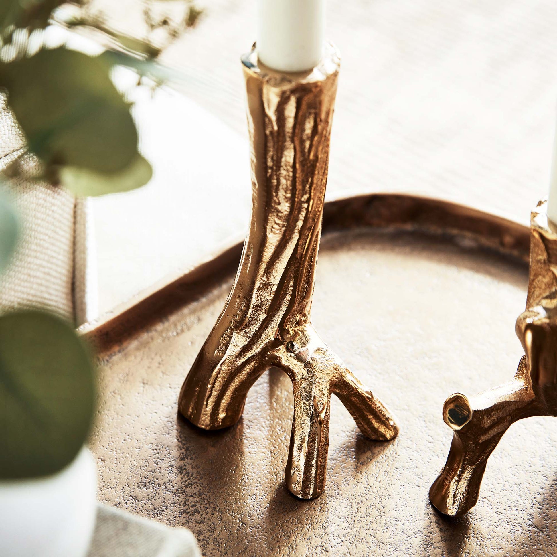 Gold driftwood taper candleholders, set of 2, stylized in living room, closeup view.