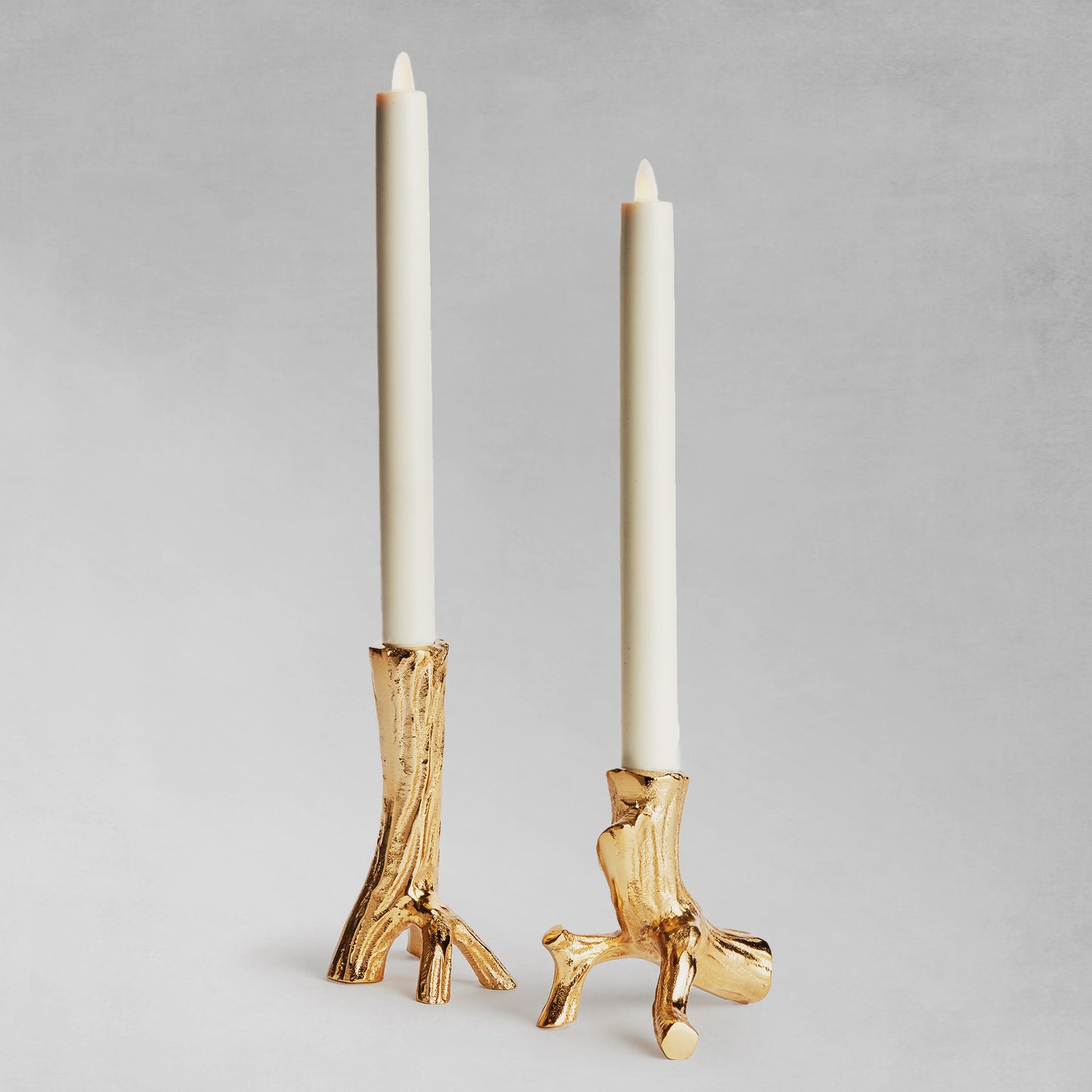 Gold driftwood taper candleholders, set of 2, with gray background.