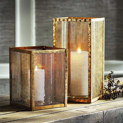 Small and large gold mesh hurricane candleholders stylized on console table.