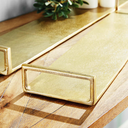 Gold narrow metal trays, set of two, closeup view, stylized on table.