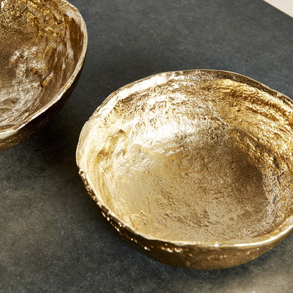 Hammered decorative gold bowls, top view, stylized on stone table.