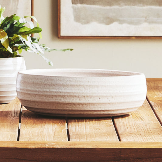 Hand-thrown white ceramic decorative bowl stylized on table.