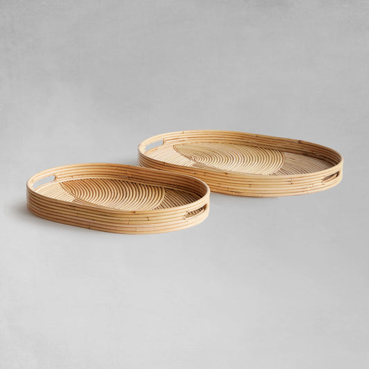 Handwoven oval rattan serving trays on gray background.