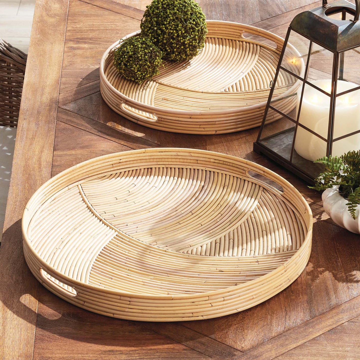 Handwoven round rattan serving trays stylized on outdoor dining table.