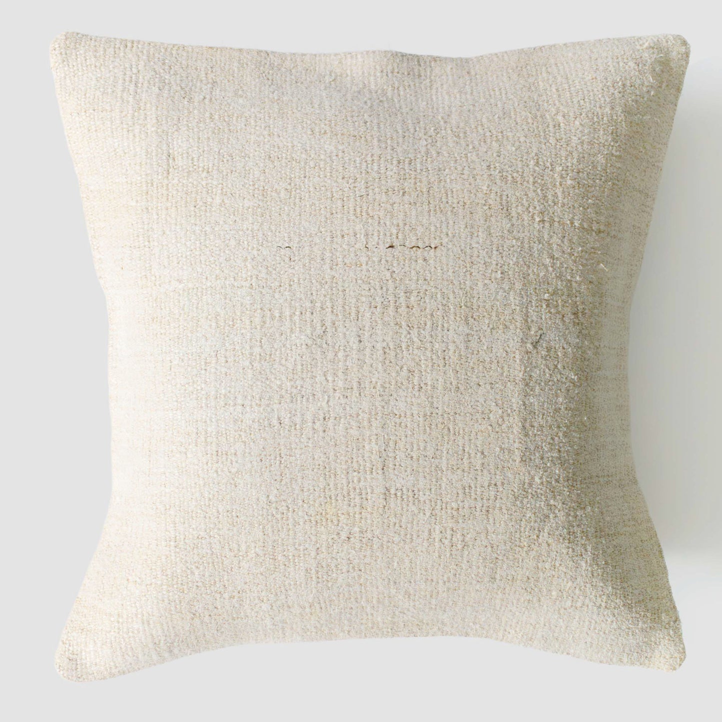 Beige textured pillow on a light gray background.