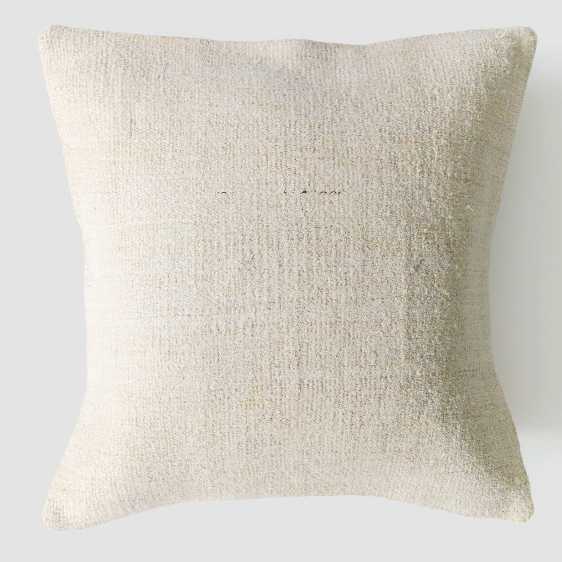 Beige textured pillow on a light gray background.