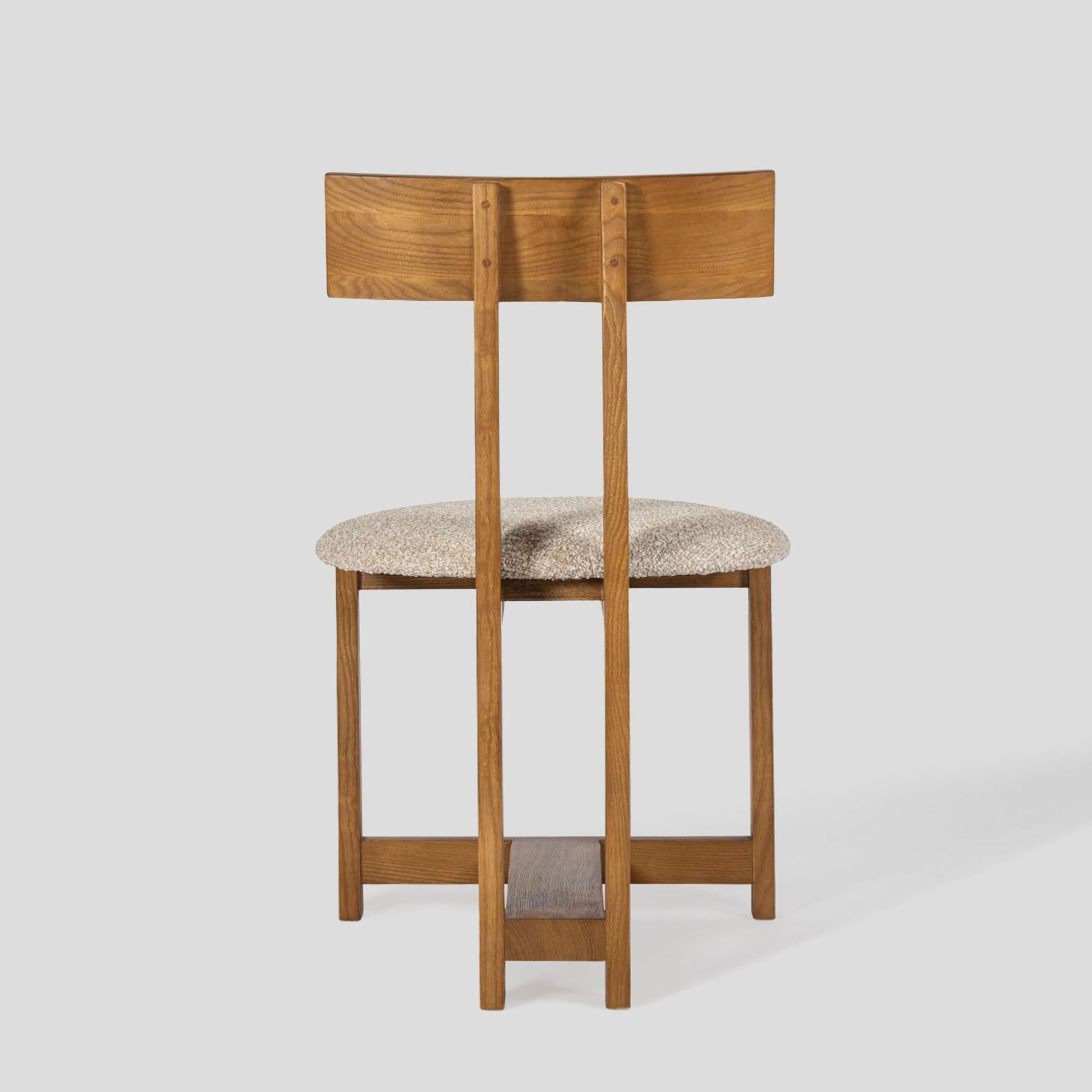 Wooden bar stool with a cushioned seat on a light gray background