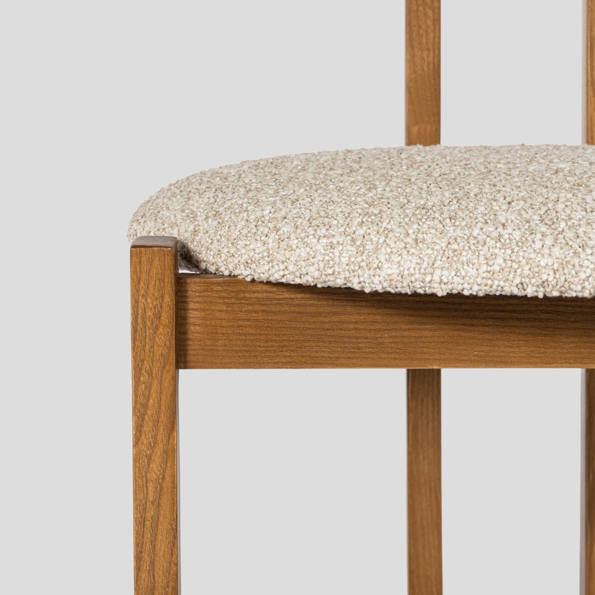 Wooden chair with a textured beige cushion on a light gray background