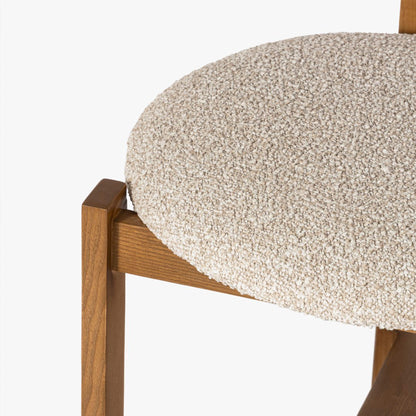 Close-up of a chair with a textured beige cushion and wooden frame on a white background