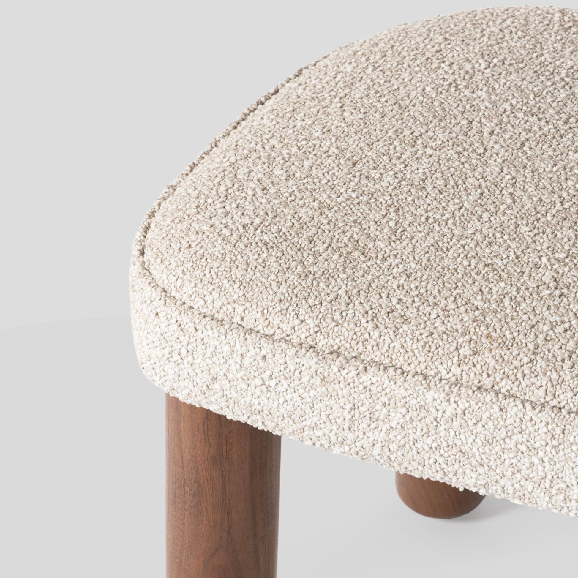 Close-up of a textured stool with wooden legs on a light gray background