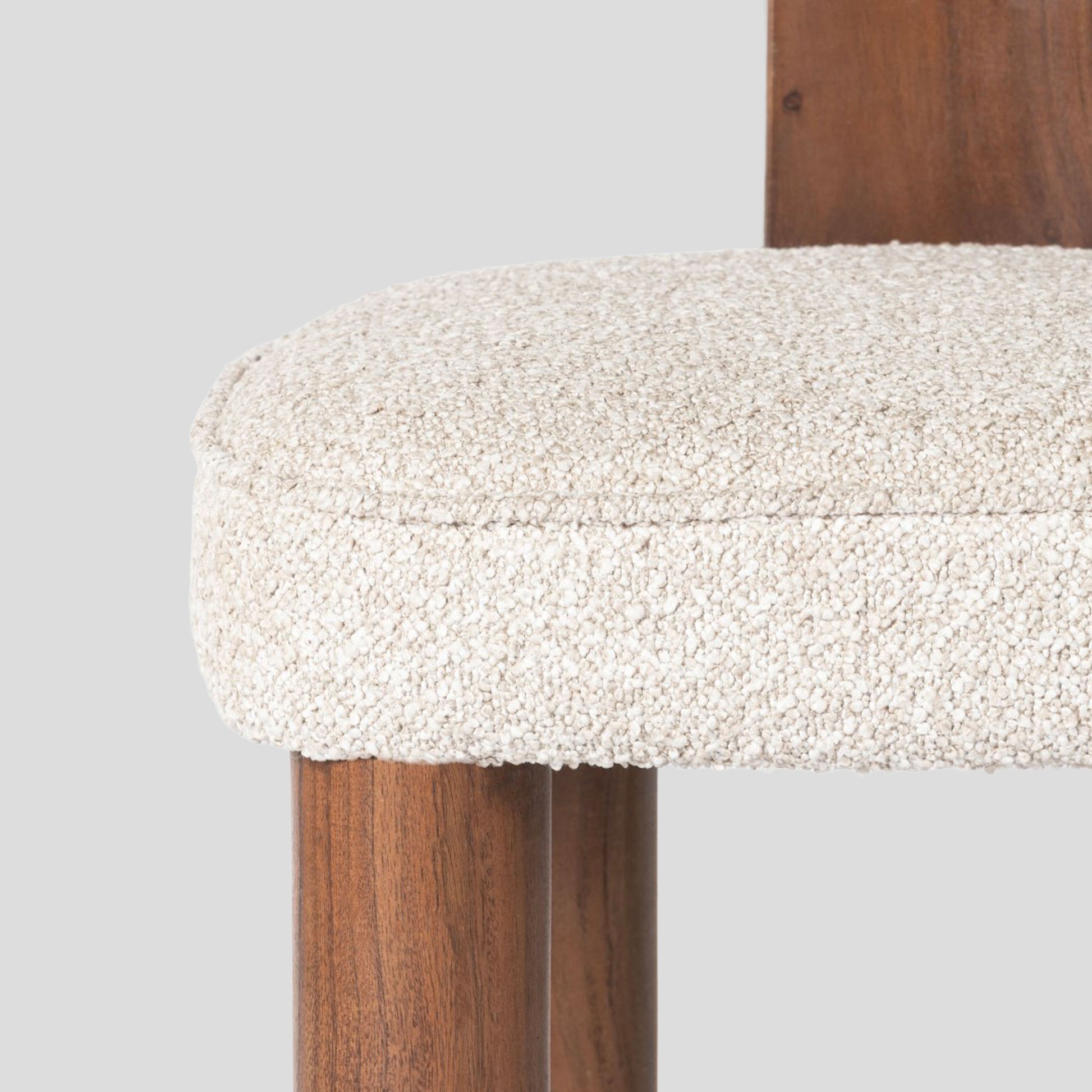 Close-up of a wooden stool with a textured white cushion on a gray background