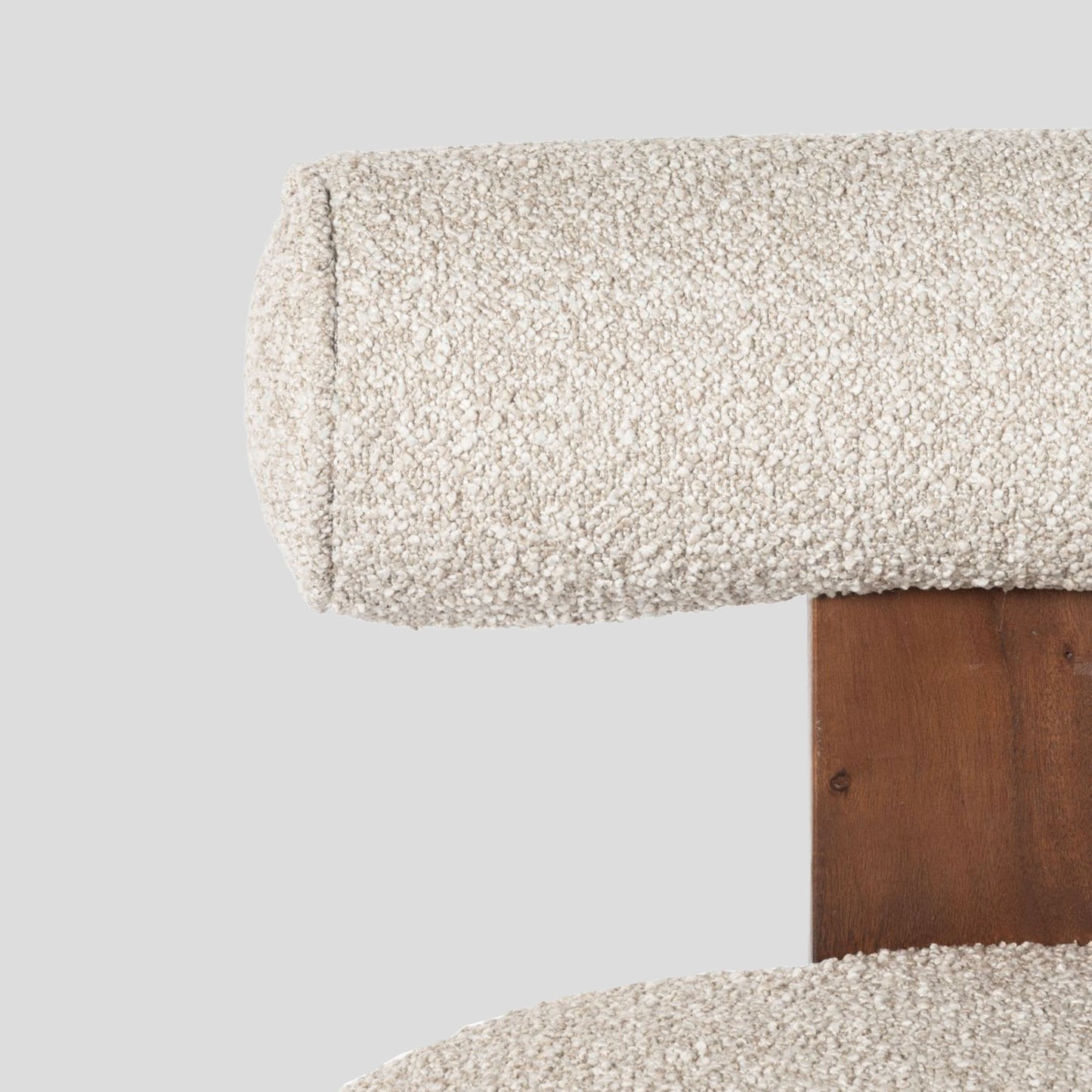 Close-up of a textured fabric surface on a wooden chair frame against a light gray background