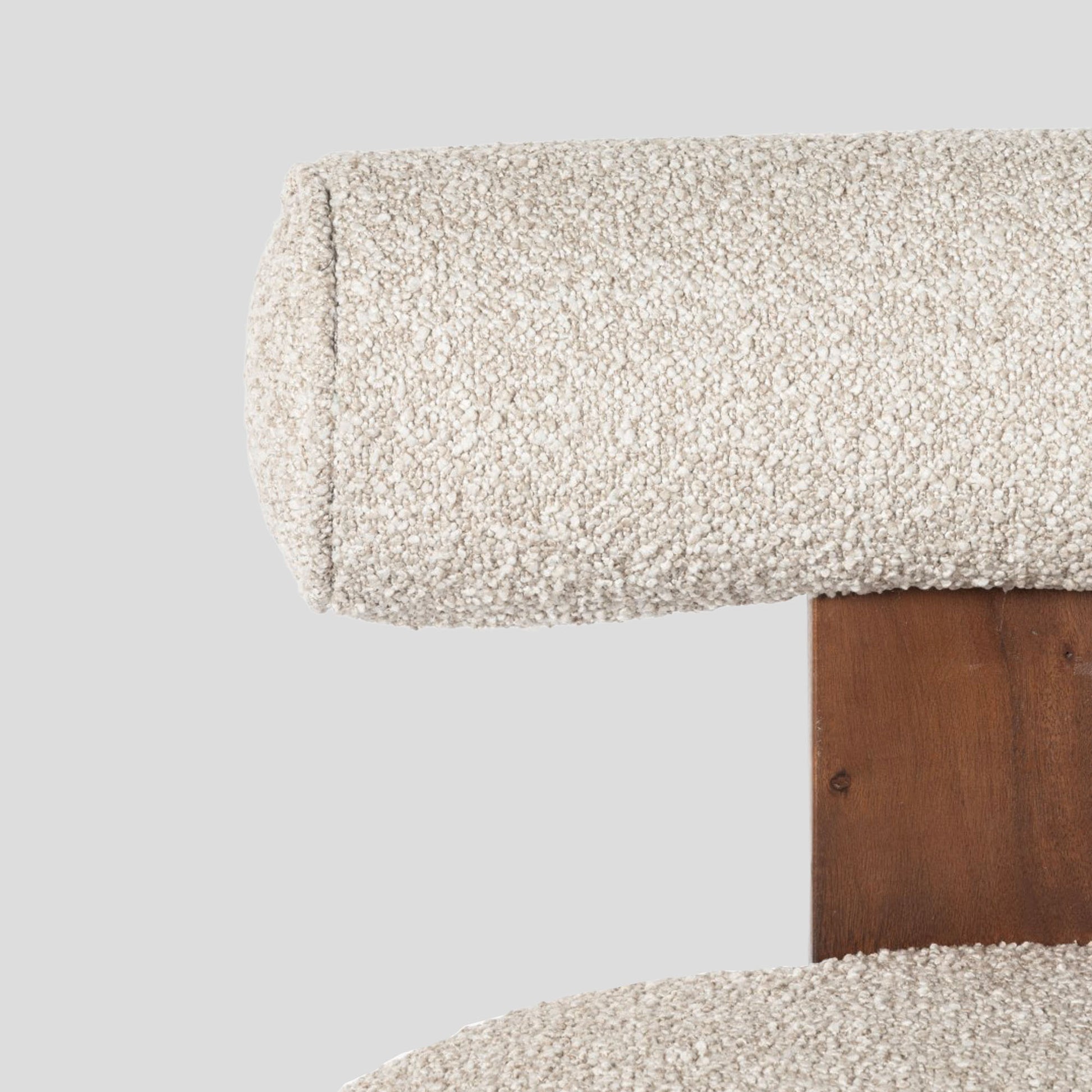 Close-up of a textured fabric surface on a wooden chair frame against a light gray background