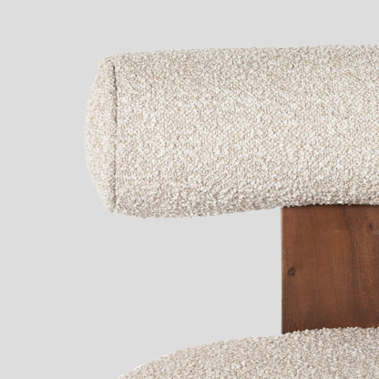 Close-up of a textured fabric surface on a wooden chair frame against a light gray background