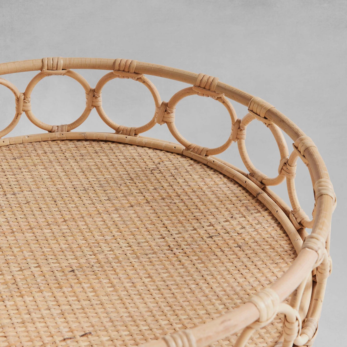 Lattice round rattan serving trays, closeup view, with gray background.