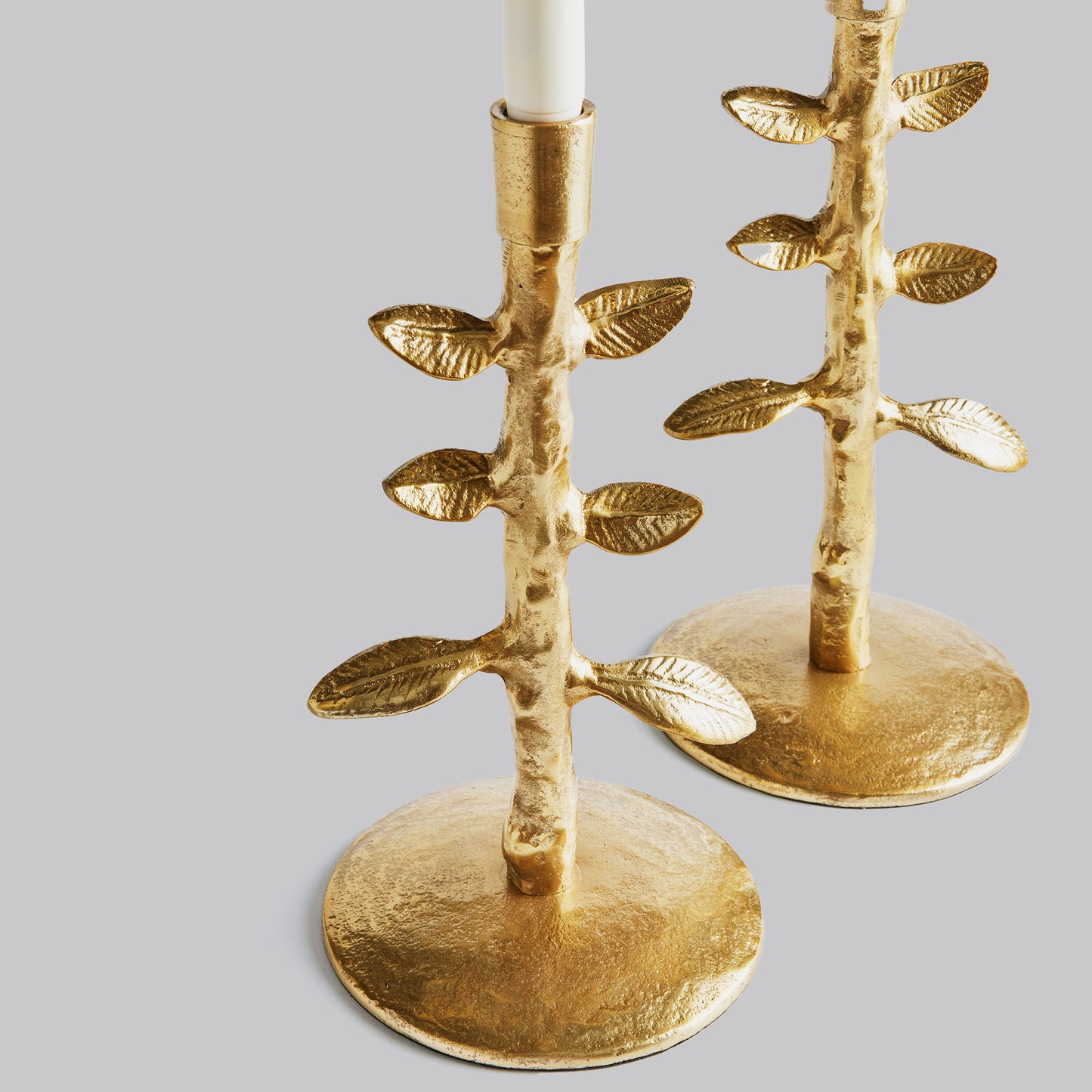 Closeup view of set of two leaf candleholders in gold.