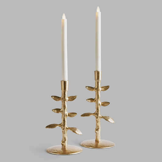 Set of two leaf candleholders in gold with gray background.