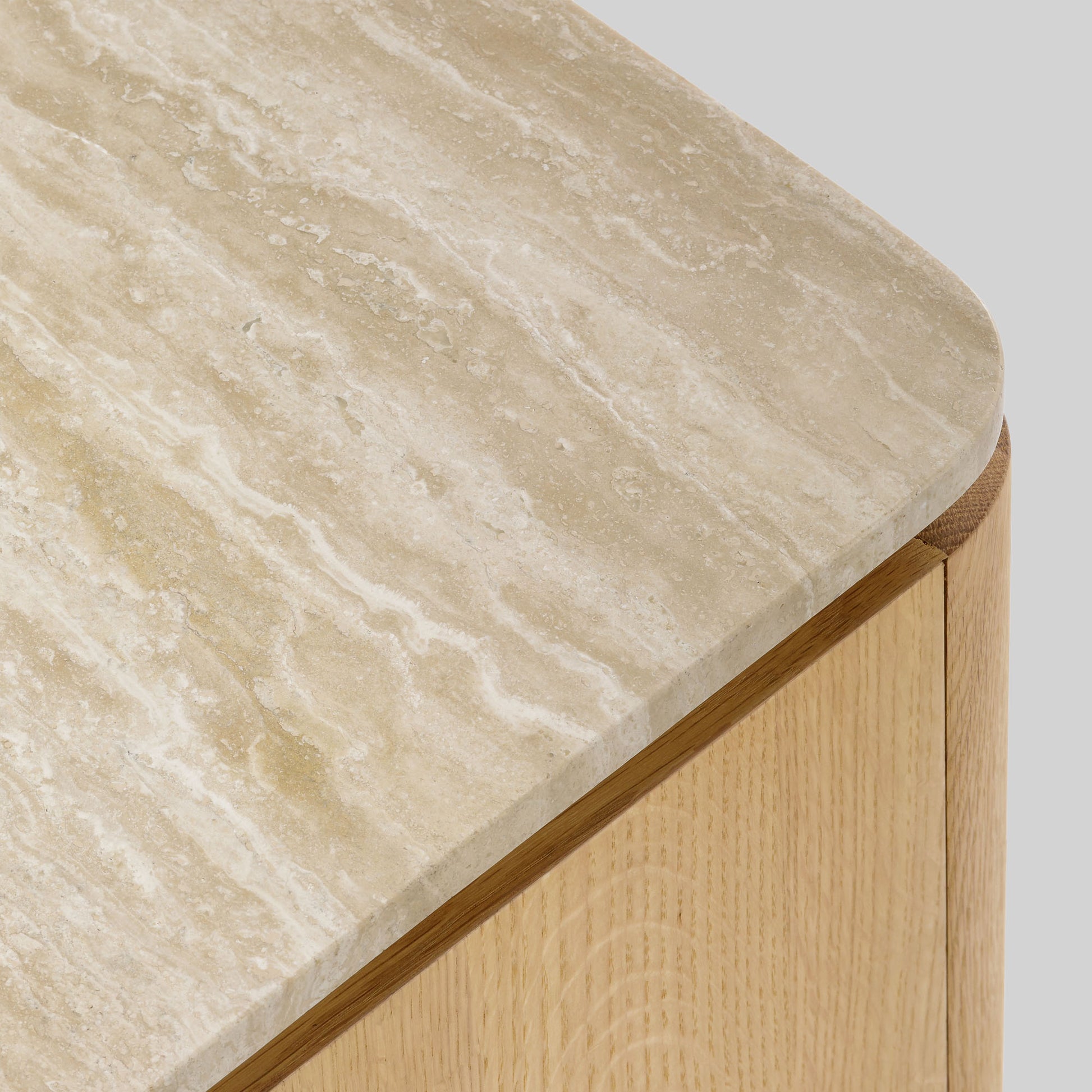 Wooden side table with a light oak finish and travertine top on a gray background.