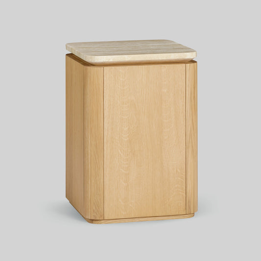 Wooden side table with a light oak finish and travertine top on a gray background.
