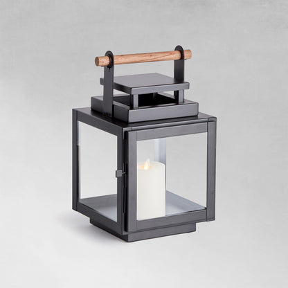 Small metal outdoor lantern with black finish with gray background.