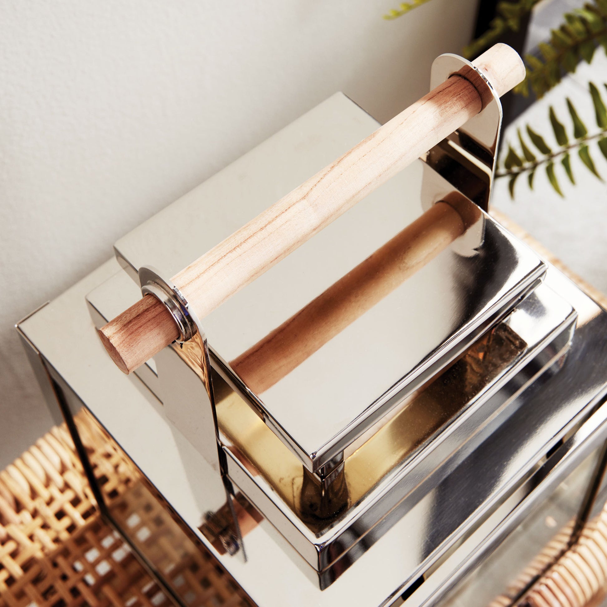 Closeup view of metal outdoor lantern with chrome finish on top of wicker table.