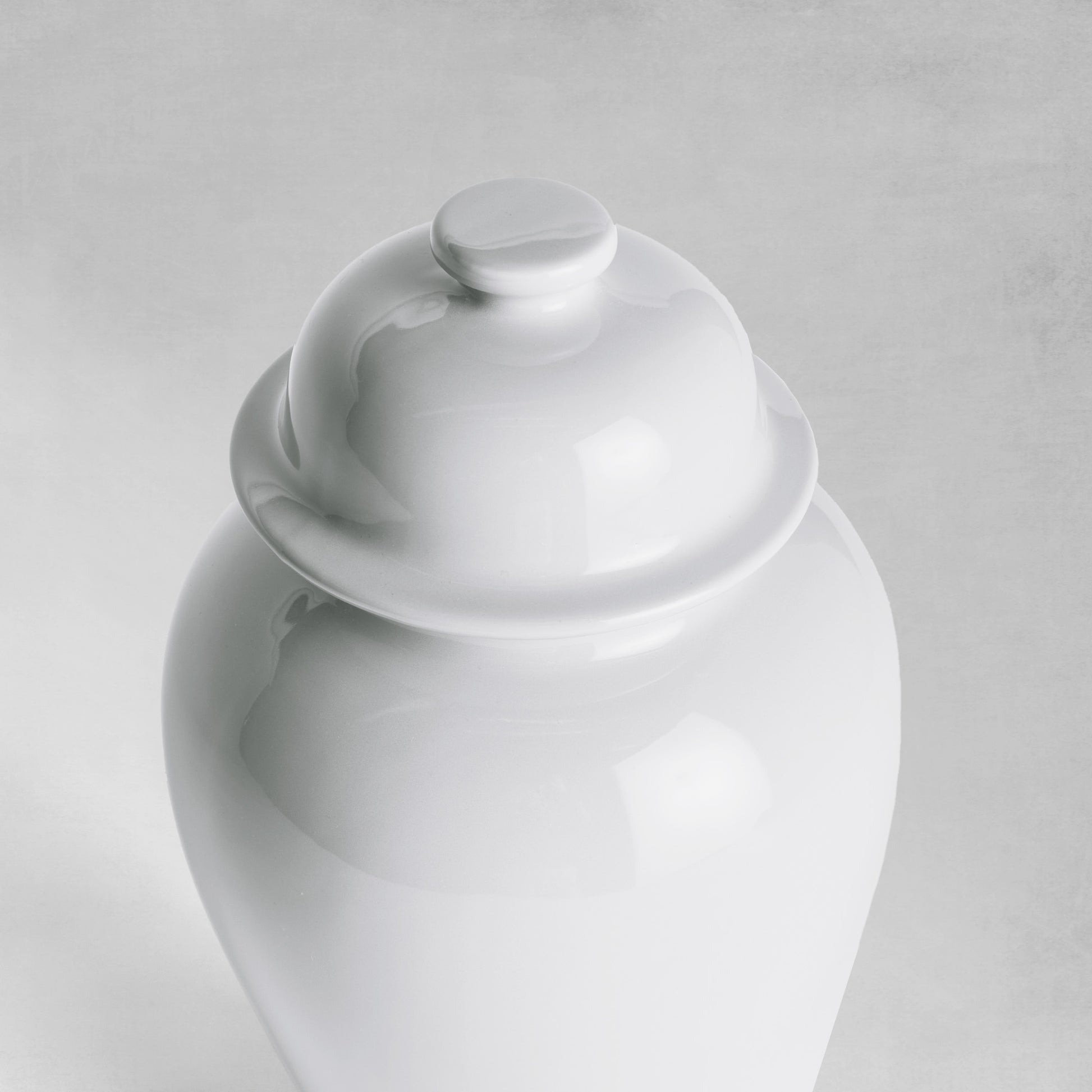 Mini white ceramic ginger jar top view with gray background.