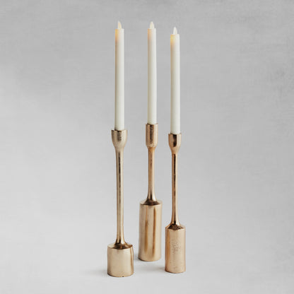 Modern gold taper candleholders, set of 3, with gray background.