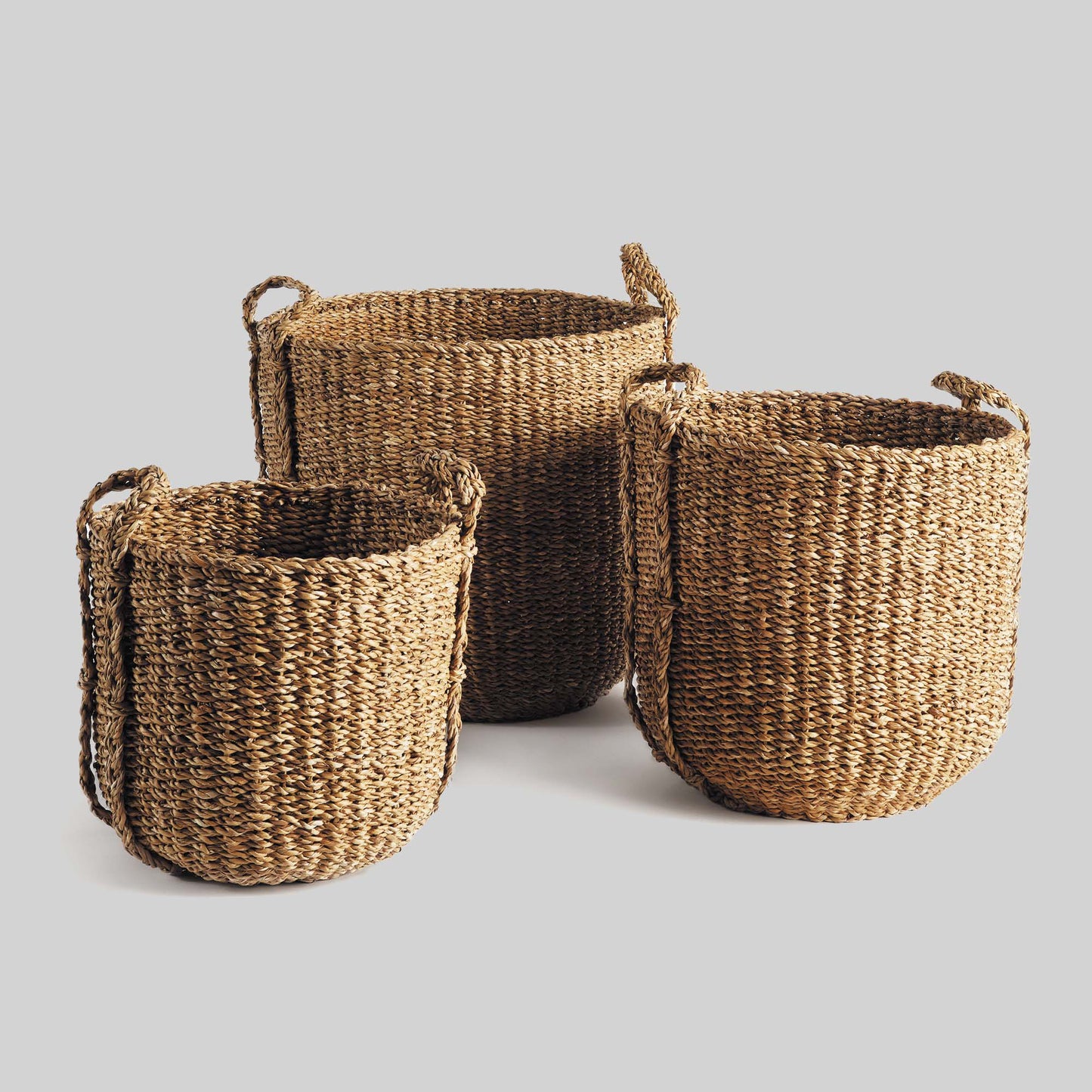 Natural woven seagrass drum baskets with gray background.