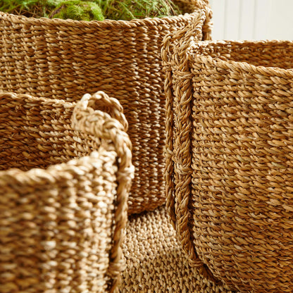 Natural woven seagrass drum baskets, side view closeup, stylized on rug.