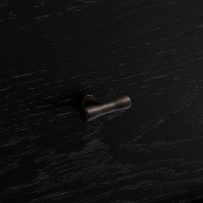 Bronze cabinet knob on a black wood nightstand.