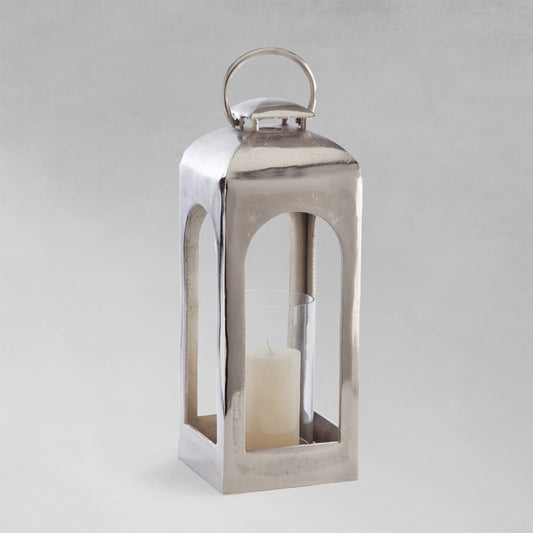 Small polished metal lantern with gray background.