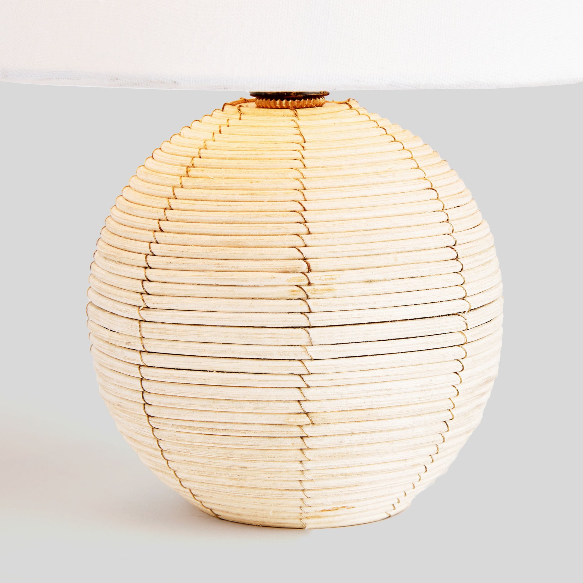 Rattan mini lamp, closeup view of lamp base, with gray background.