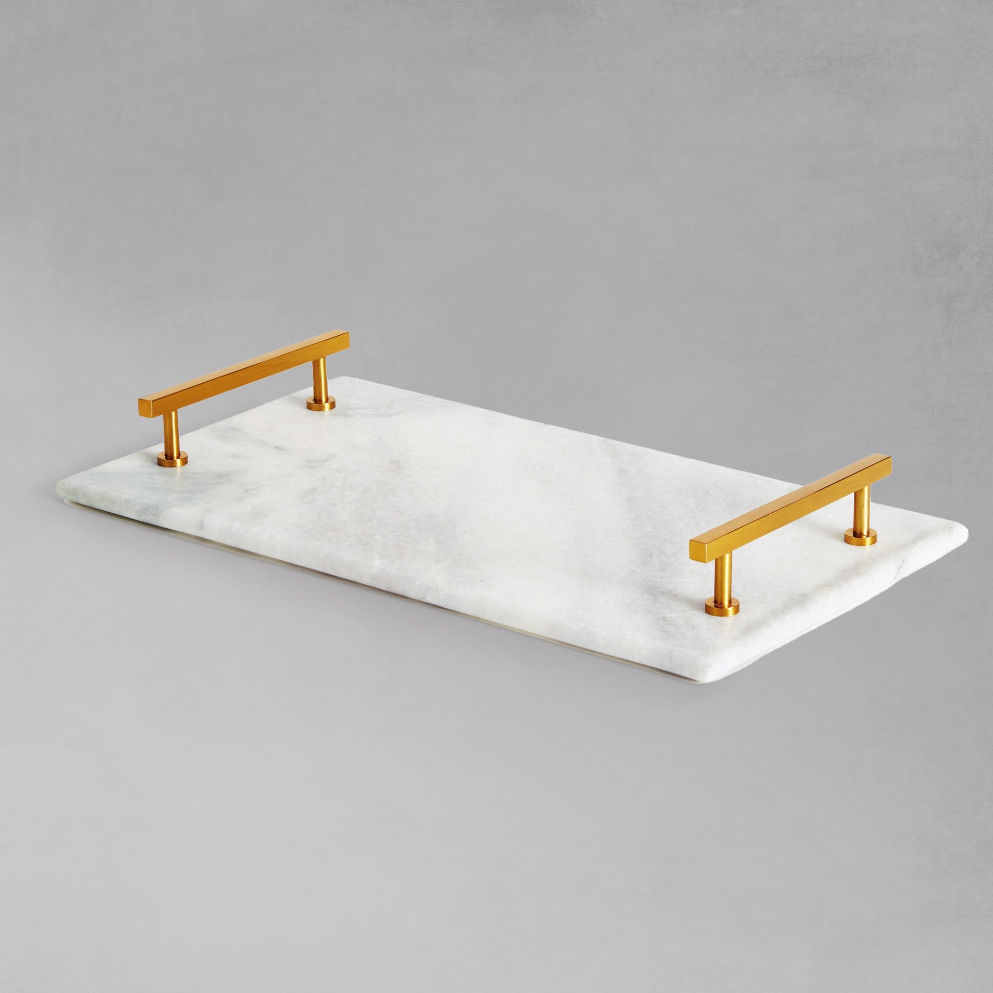 Rectangular marble serving tray with brass accents with gray background.