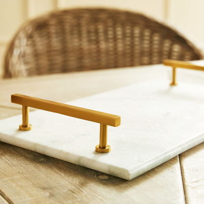 Rectangular marble serving tray with brass accents, closeup view.