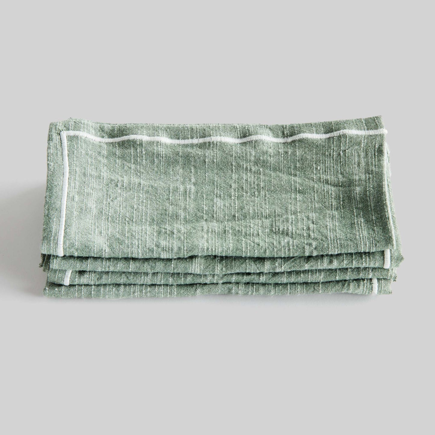 Sage green and white square cotton dinner napkins set of 4, folded and stacked, with gray background.