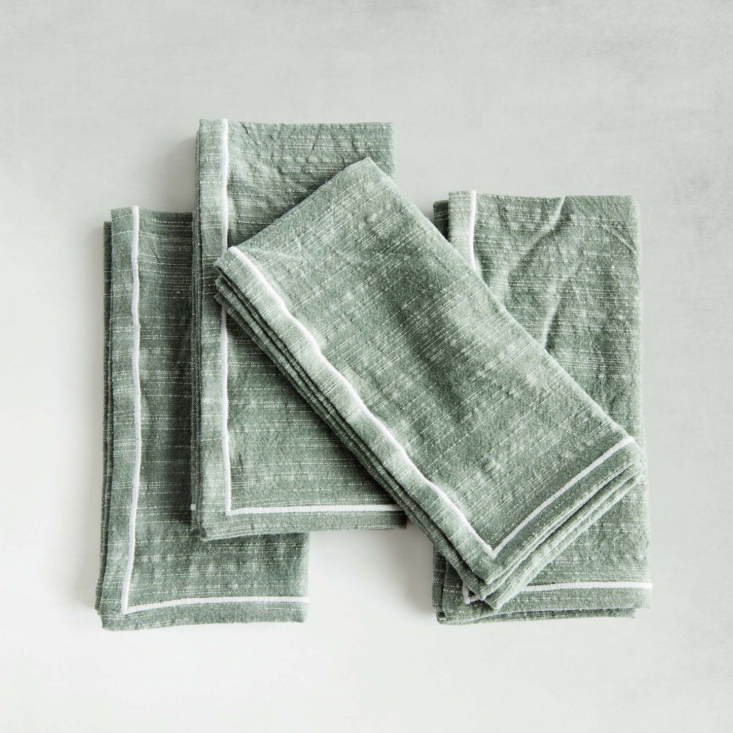 Sage green and white square cotton dinner napkins set of 4 with gray background.