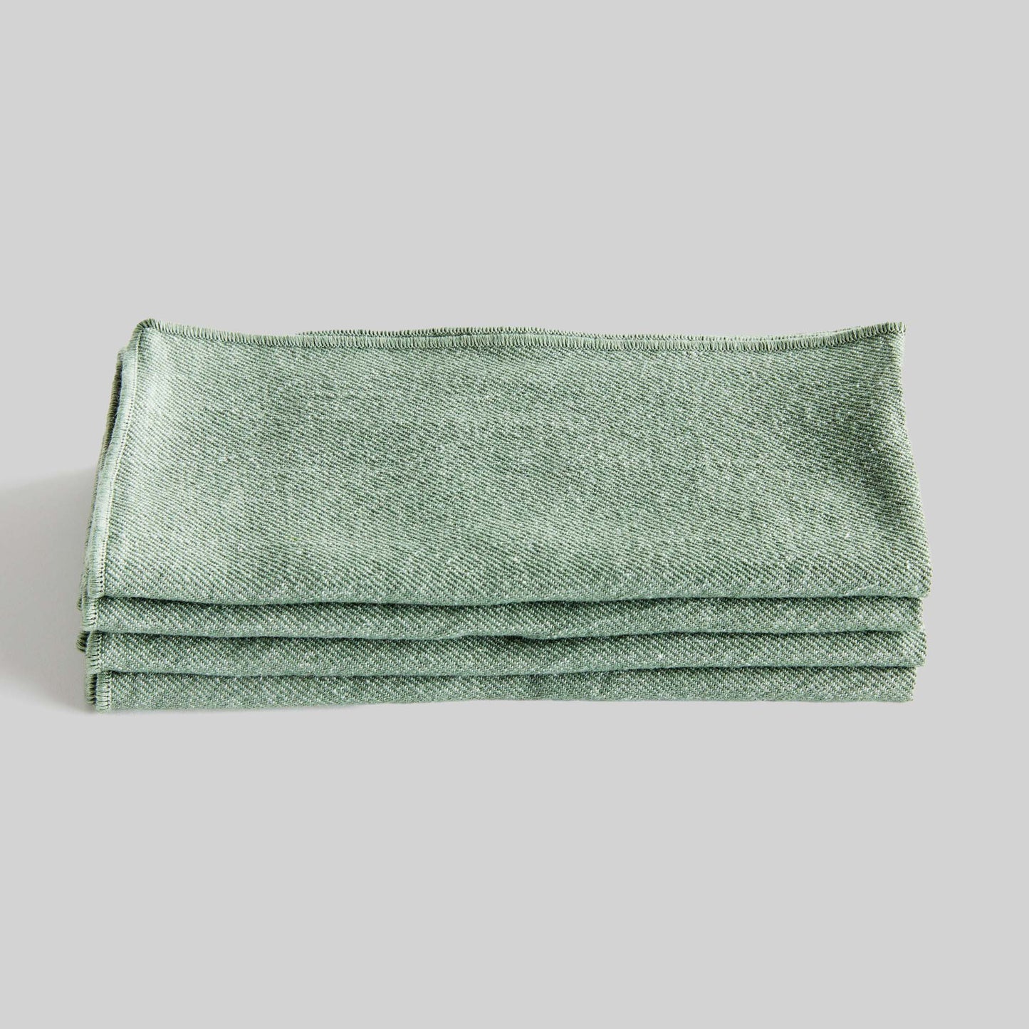 Sage green square cotton dinner napkins set of 4, folded and stacked, with gray background.