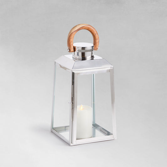 Small stainless steel outdoor lantern with teak wood handle on gray background.