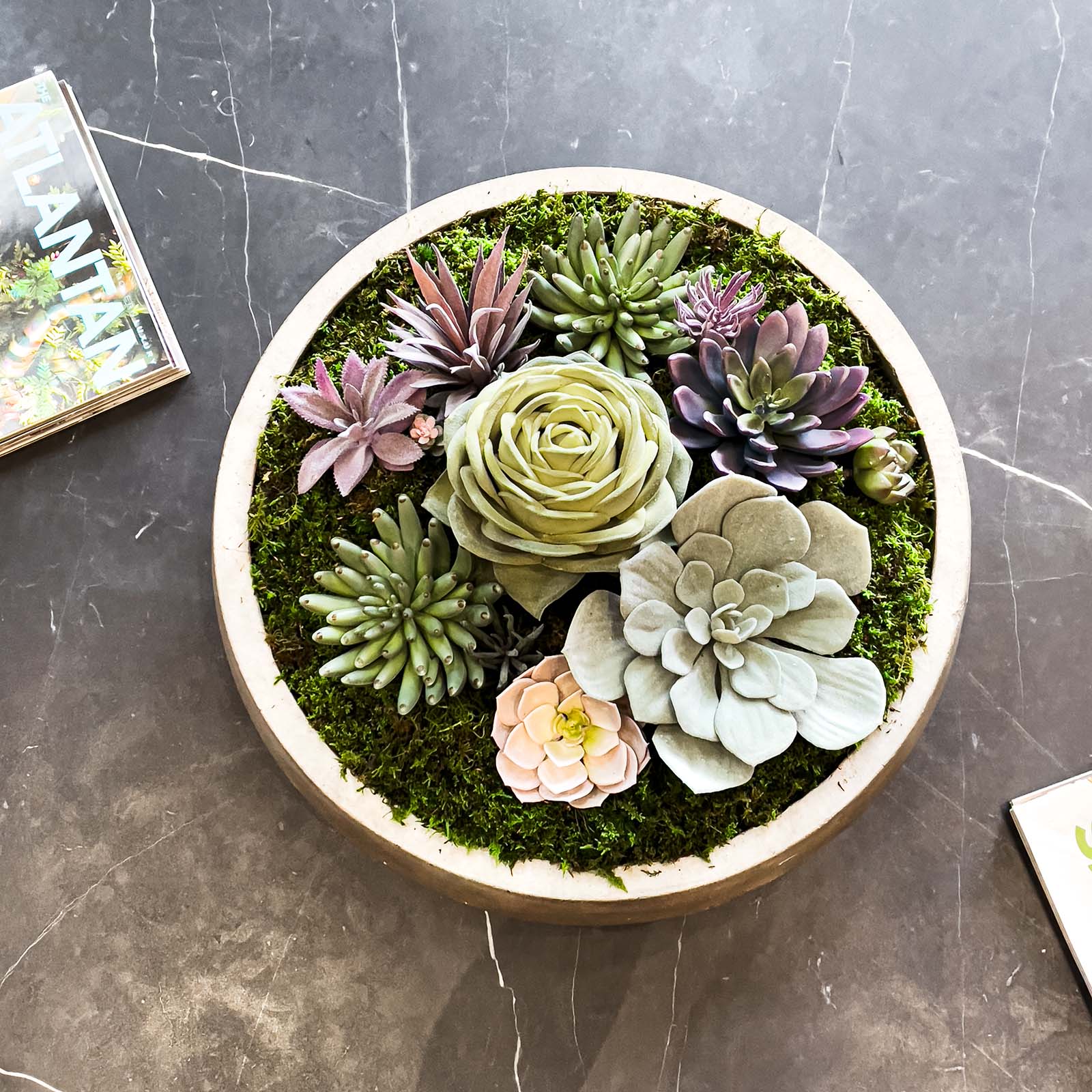 Faux succulent arrangement in concrete vessel on soapstone table.