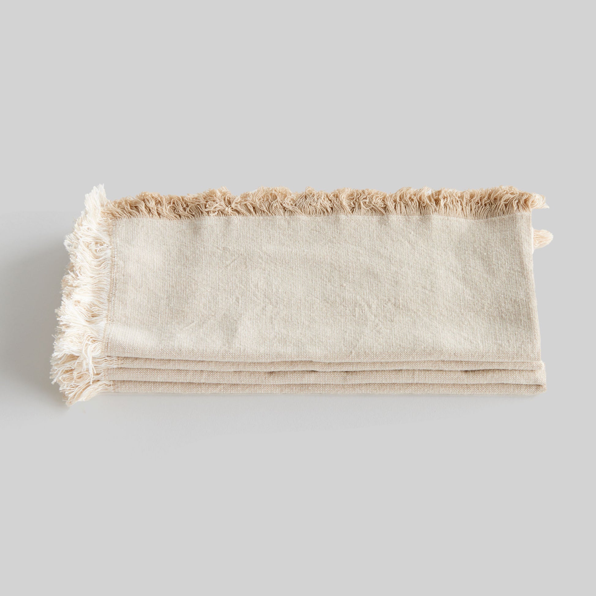 Tan fringe square cotton dinner napkins set of 4, closeup view of stacked napkins.